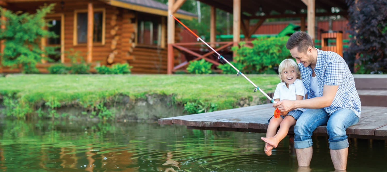 Father helping young son fish off a dock