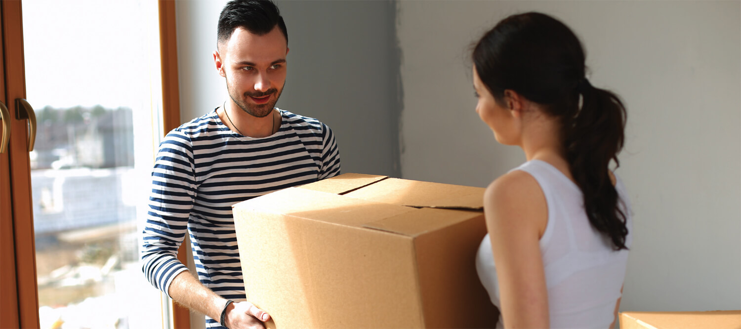 Couple carrying boxes into a new home