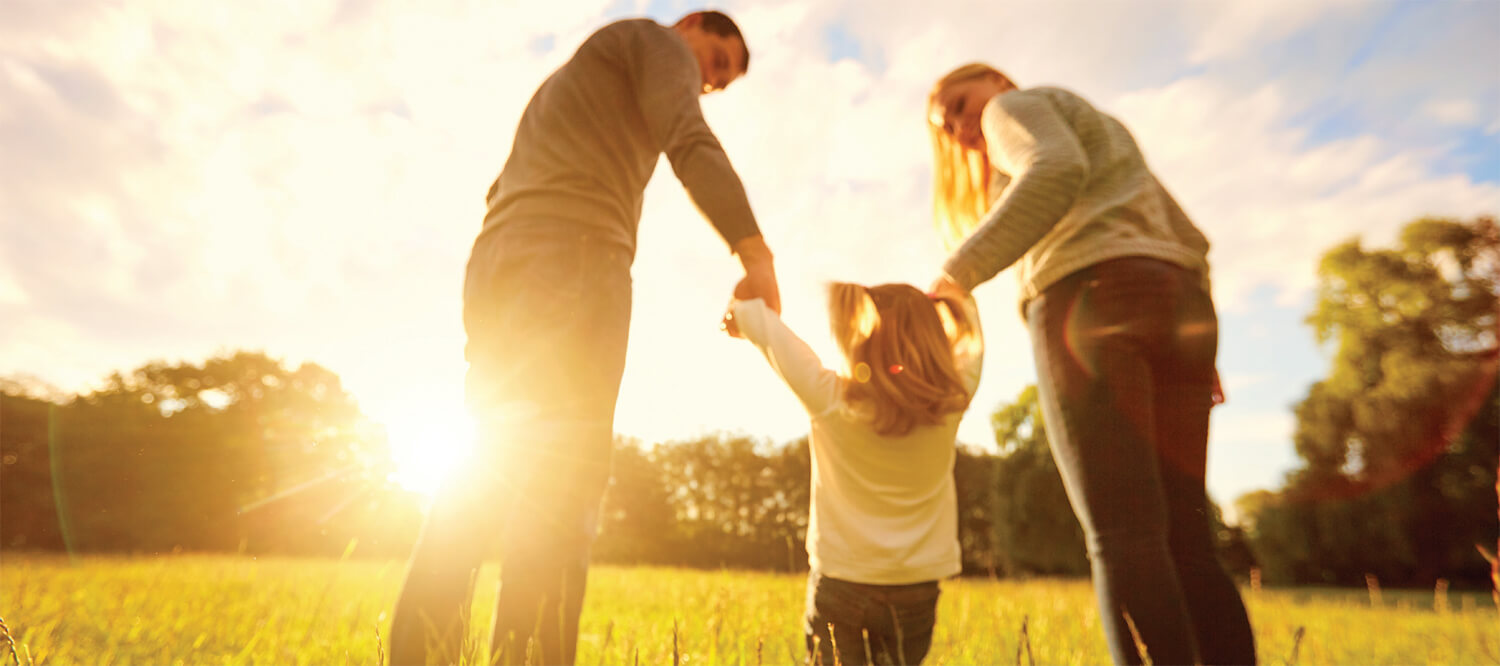Child taking a walk, hand-in-hand with mom and dad during sunrise